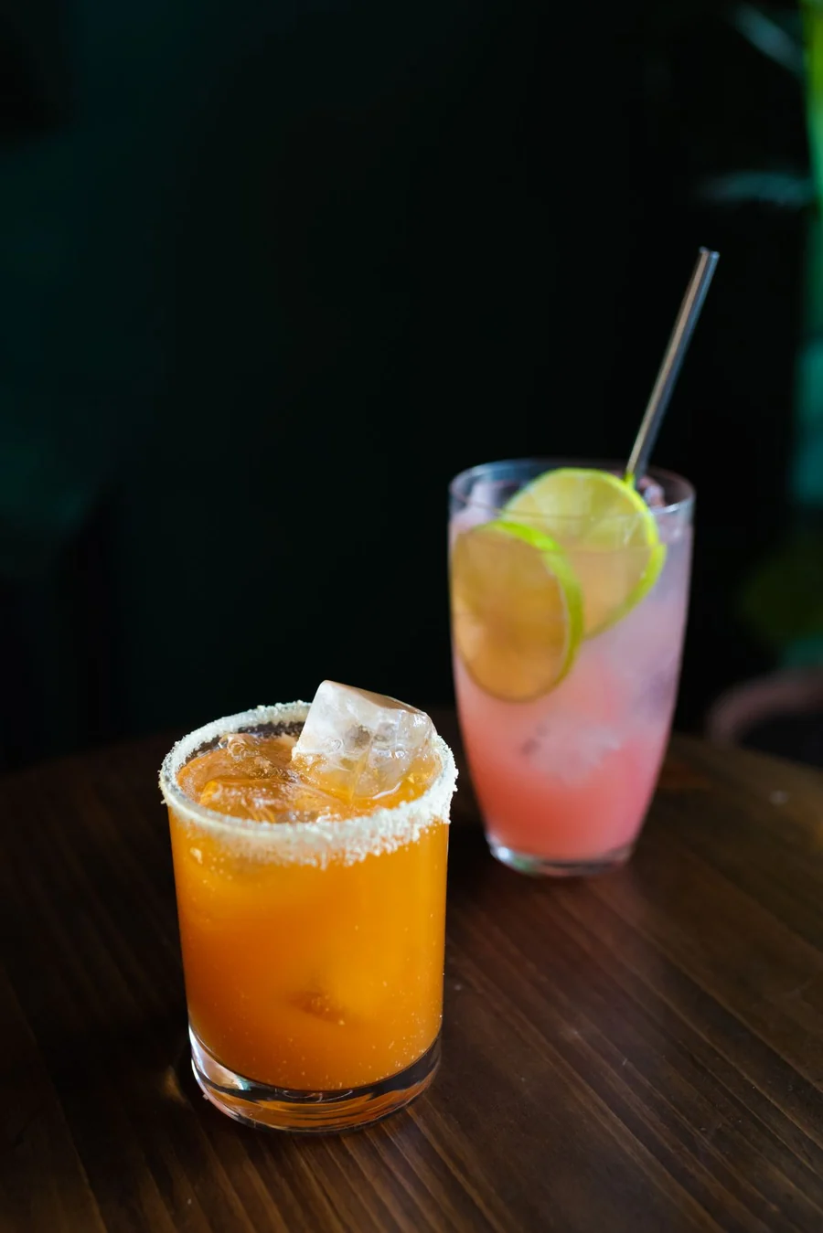 Two colourful citrus cocktails on a wooden table
